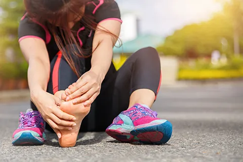 female runner holding painful foot